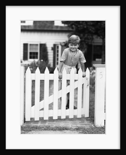 1940s Child Boy Standing Swinging On White Picket Fence Gate Smiling Looking At Camera by Anonymous