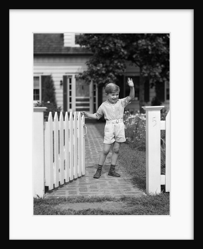 1940s Boy Standing Near White Picket Fence Gate Waving by Anonymous