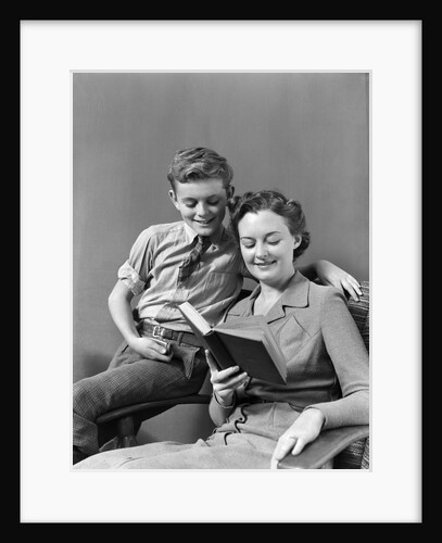 1930s 1940s Boy Son Perched On Arm Of Chair With Woman Mother Sitting In The Chair Reading A Book by Anonymous
