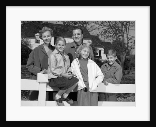 1960s Portrait Smiling Family Father Mother Two Daughters Son By White Fence In Front Of Suburban House In Autumn by Anonymous