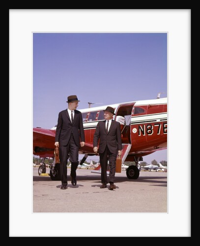 1960s Two Businessmen In Suits And Hats Carrying Briefcases Walking From A Small Twin Prop Business Airplane Talking by Anonymous