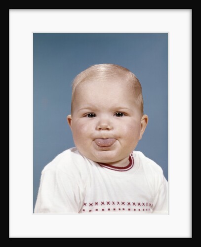 1960s Portrait Of Cute Blond Chubby Baby Looking At Camera Sticking Out Tongue by Anonymous