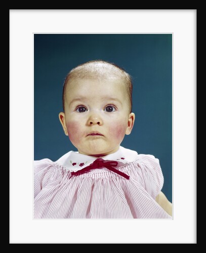 1960s Portrait Baby Girl Silly Facial Expression Red Bow At Collar Looking At Camera by Anonymous