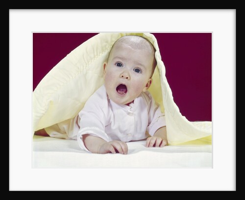 1960s Baby Mouth Wide Open Peeking Out From Under Yellow Blanket Looking At Camera by Anonymous