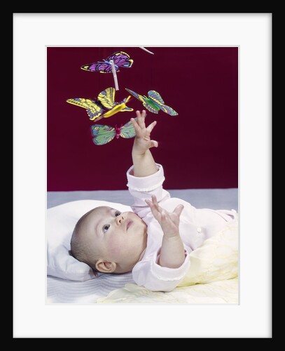 1960s Baby Reaching Up To Grab Mobile Of Butterflies by Anonymous