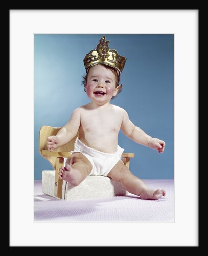 1960s Smiling Happy Baby Wearing Crown Sitting On Booster Seat Chair Throne Looking At Camera by Anonymous