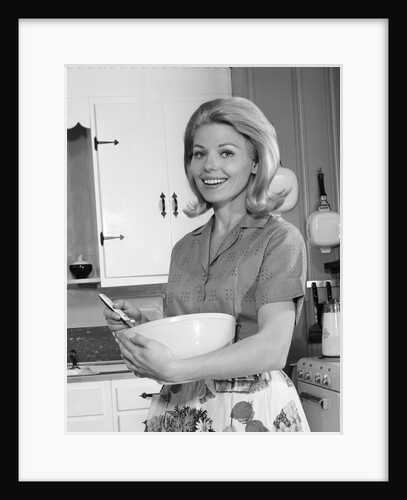 1960s 1970s smiling blond housewife in kitchen holding mixing bowl by Anonymous