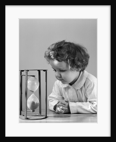 1940s young girl leaning on table staring at hourglass by Anonymous