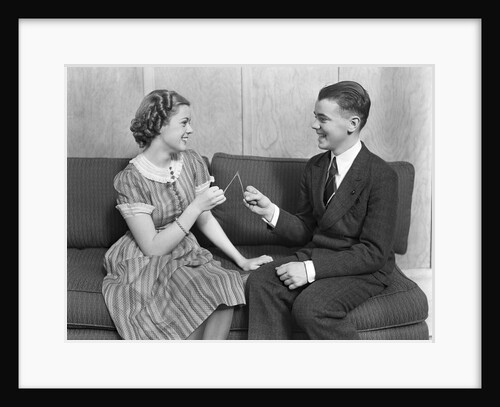 1930s teen boy and girl sitting on a sofa holding wishbone by Anonymous