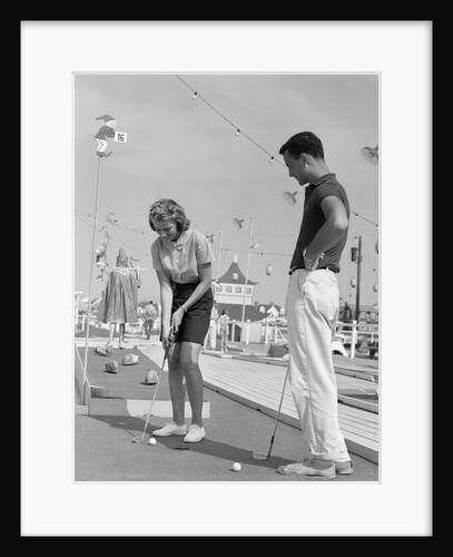 1950s 1960s teenage couple playing miniature golf by Anonymous