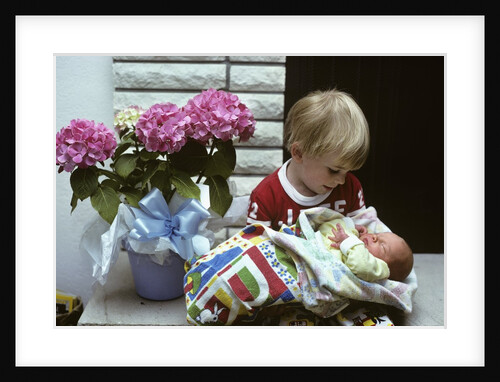 1970s boy holding a newborn baby by Anonymous