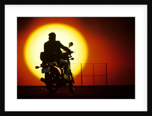 1980s silhouette of anonymous man on motorcycle driving toward rising setting sun by Anonymous