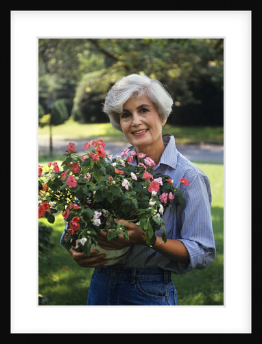 Smiling senior woman holding garden flowers by Anonymous