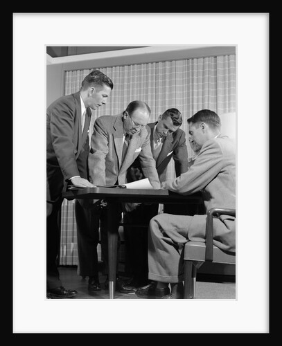 1950s group of businessmen looking at a blueprint on a table by Anonymous