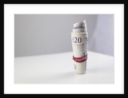 A roll of twenty pound notes on a table by Anonymous