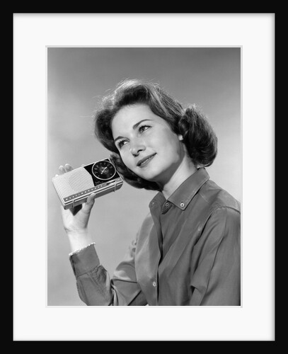 1960s smiling teenage girl listening to portable radio by Anonymous