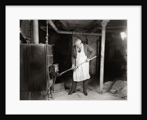 1940s elderly man shoveling coal into furnace in a basement by Anonymous