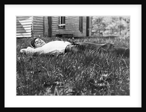 Young man lays in the grass, ca. 1912. by Anonymous