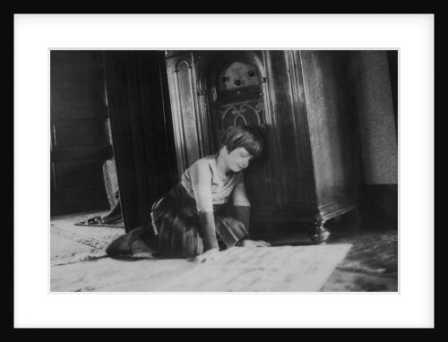 Young girl listens to the radio while reading paper, ca. 1930. by Anonymous