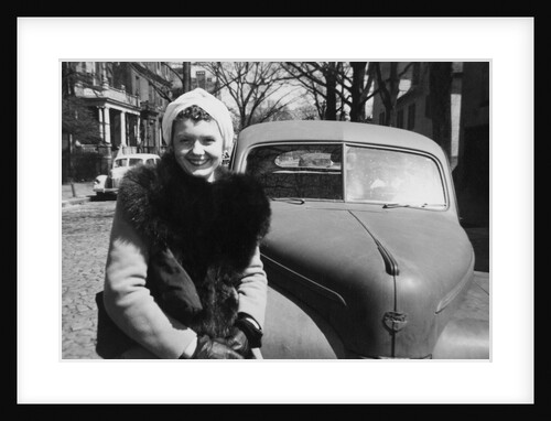Young woman sits on bumper of her car, ca. 1942. by Anonymous