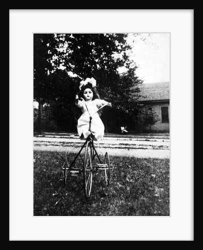 Large play doll sits on a period tricycle, ca. 1925. by Anonymous