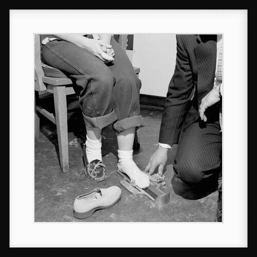 Salesmen helps woman with safety work shoes, ca. 1943 by Anonymous