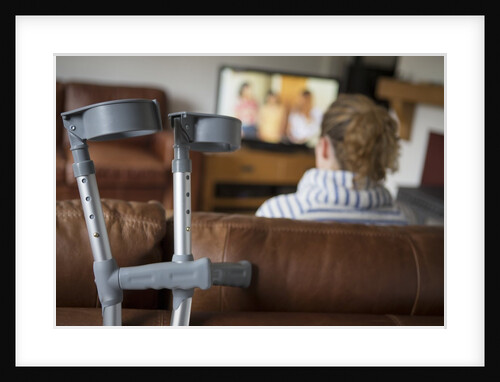 Woman watching TV with crutches by Anonymous