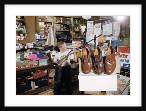 Boy Holding Shotgun in Sporting Goods Store by Anonymous