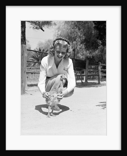 Woman Kneels and Pets Baby Ostrich by Anonymous