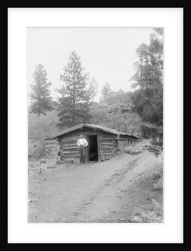 Man Standing in Front of Log Cabin by Anonymous
