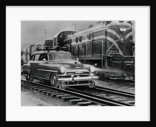Car Riding the Rails Next to a Train by Anonymous