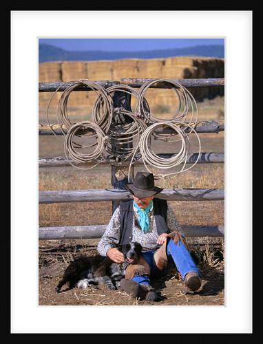 Cowboy and Dog Sitting Against Fence by Anonymous