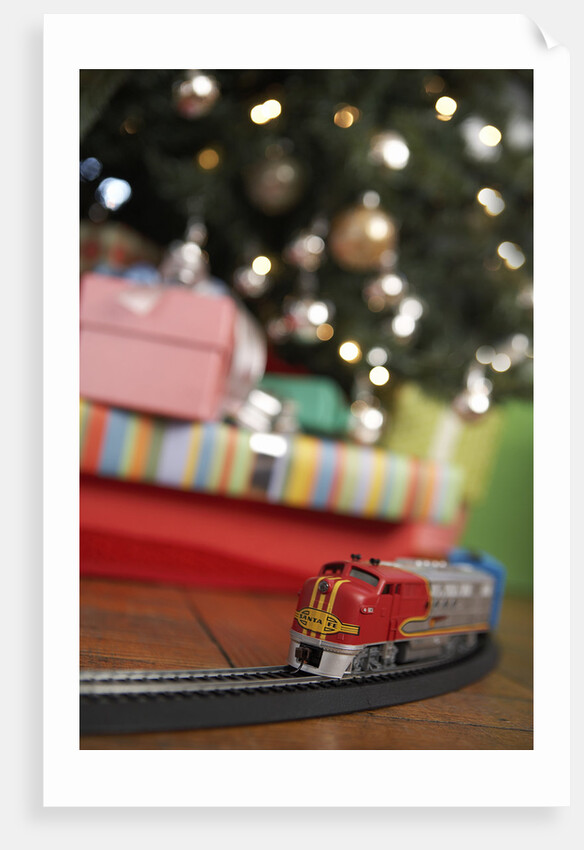 Toy train running beneath Christmas tree by Anonymous