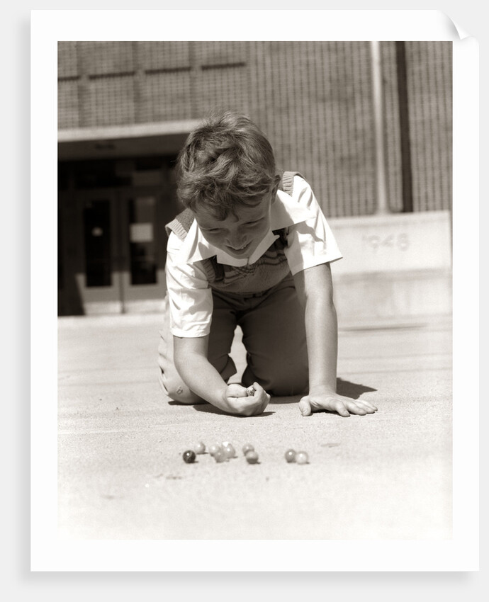 1950s Boy Ready To Shoot Kneeling On School Yard Ground Playing Game Of Marbles by Anonymous