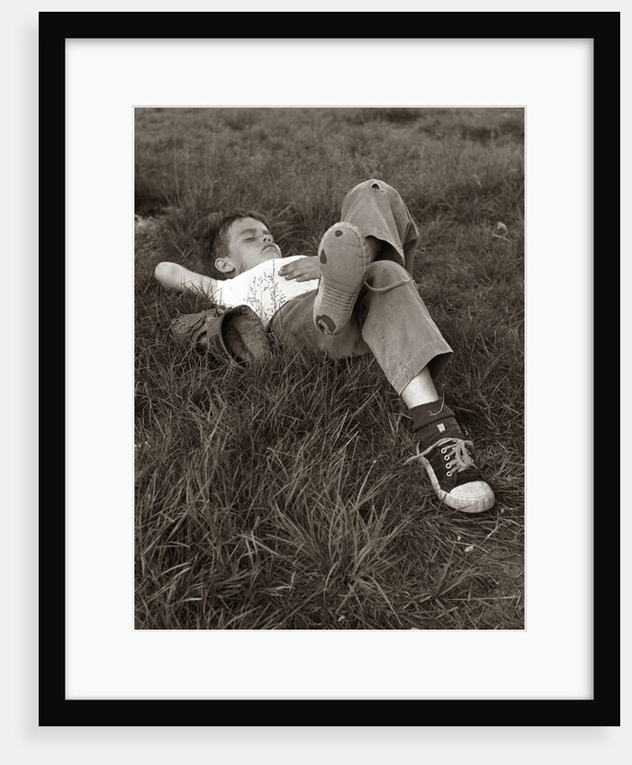 1960s Boy Sleeping In Grass Legs Crossed Holes In Sneakers Baseball Mitt By His Side by Anonymous