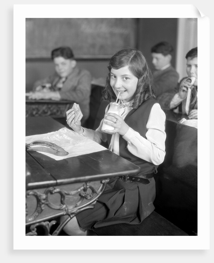 1920s School Girl Eating Lunch At Her Desk Drinking From A Bottle Of Milk Holding A Sandwich by Anonymous