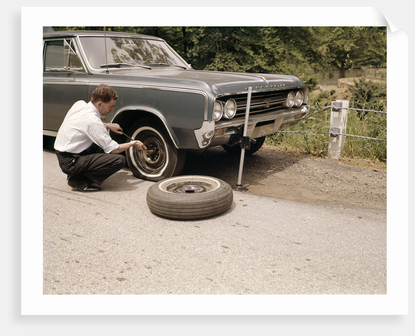 1960s Man Changing Flat Tire On Car At Side Of Rural Road Car Jack Tools Tire Iron by Anonymous