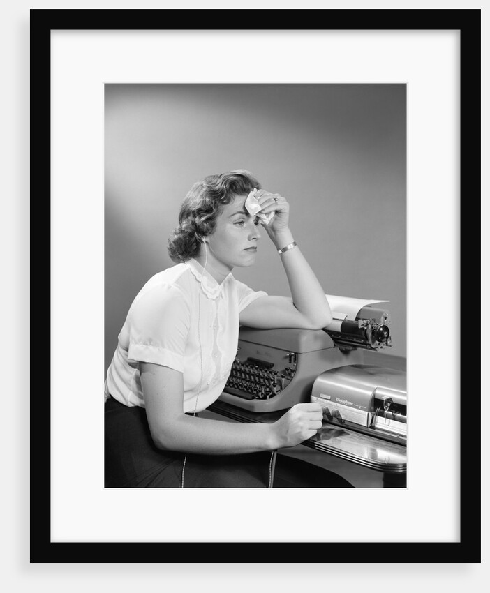 1950s Ailing Secretary Sitting At Desk With Typewriter And Dictation Machine Holding Handkerchief To Forehead by Anonymous