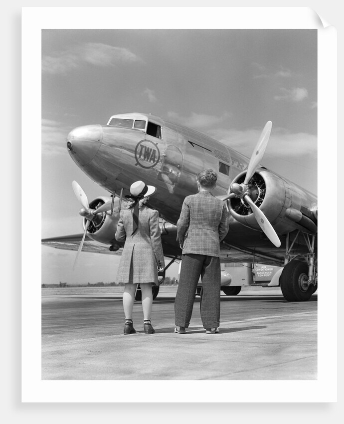 1940s Rear View Of Boy and Girl Standing Together Looking At Propeller Airplane Outdoor by Anonymous