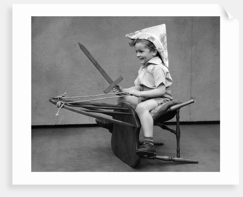1930s Boy Playing Wooden Sword Paper Hat Riding Chair Like A Horse by Anonymous