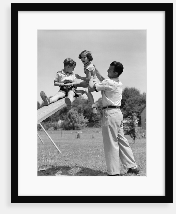 1950s Father Lifting Son And Daughter Onto A Playground Seesaw Outdoor by Anonymous