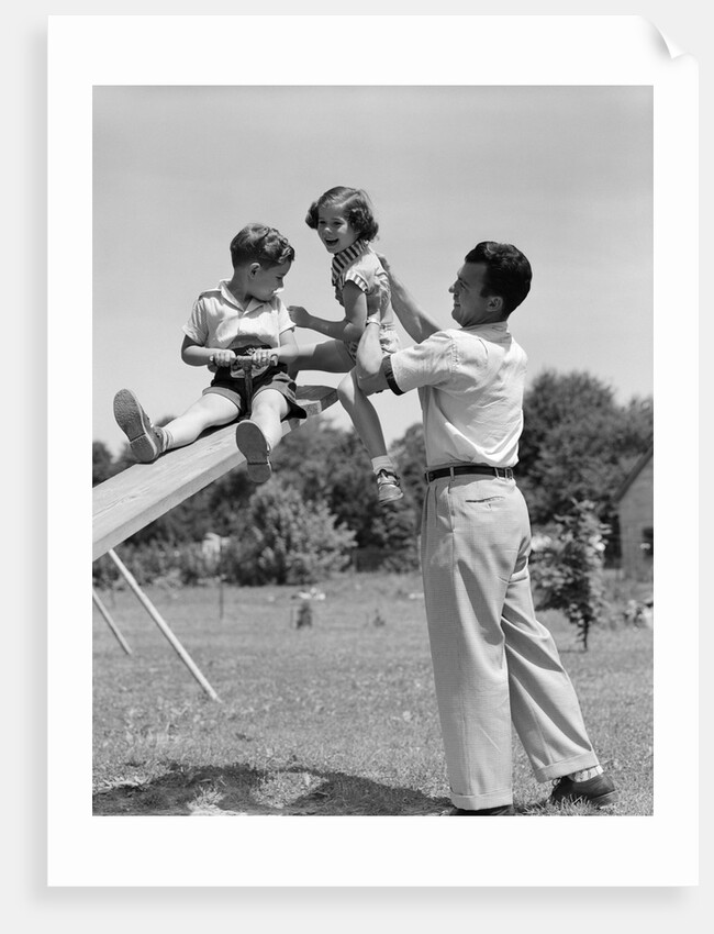 1950s Father Lifting Son And Daughter Onto A Playground Seesaw Outdoor by Anonymous