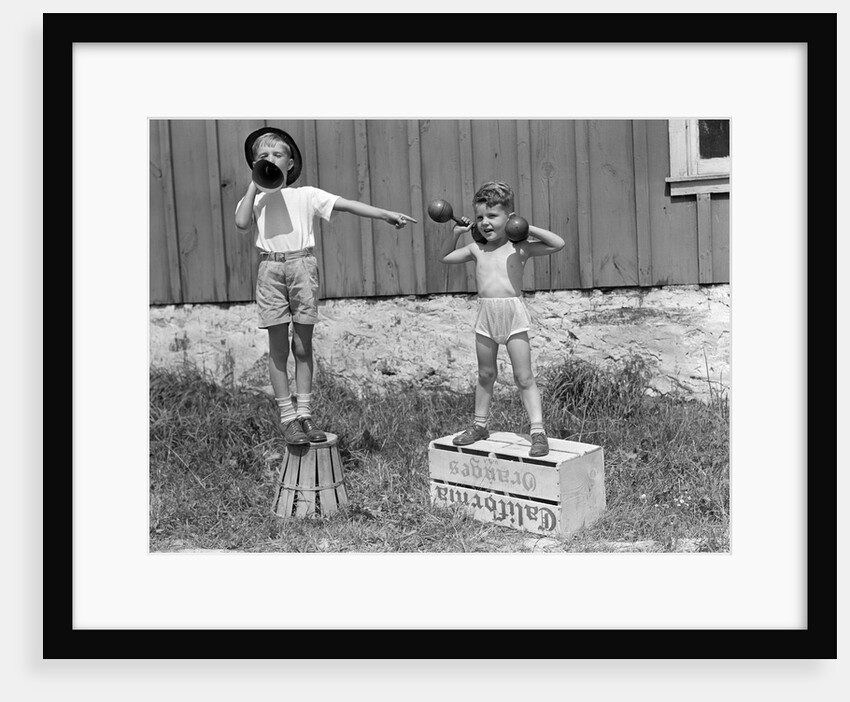 1930s 1940s Boys Playing Carnival Strongman One Lifting Dumbbells Other Announcing Act Through Megaphone by Anonymous
