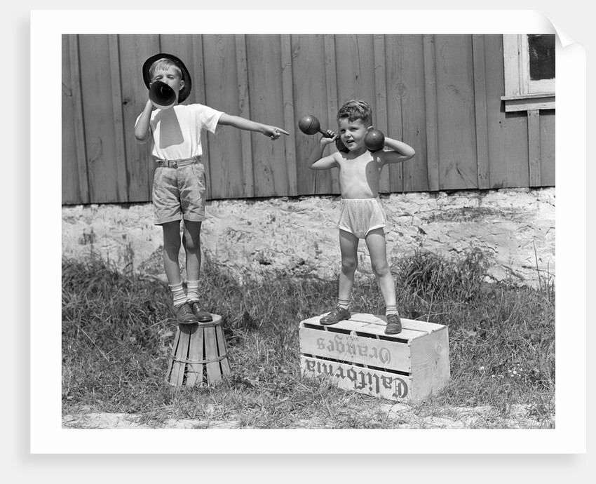 1930s 1940s Boys Playing Carnival Strongman One Lifting Dumbbells Other Announcing Act Through Megaphone by Anonymous