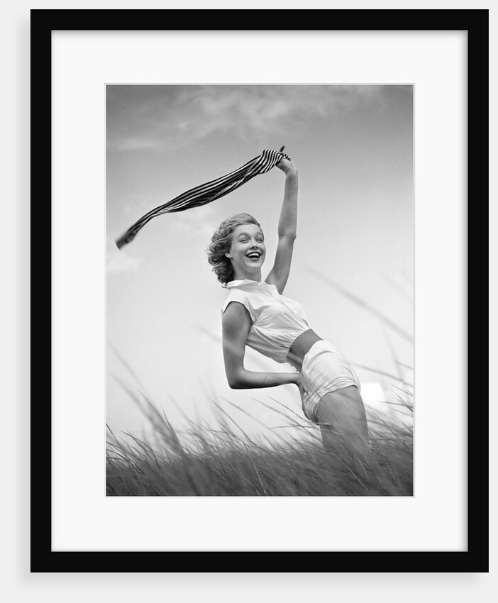 1950s 1960s Young Woman Bending Back Holding Scarf In The Wind Standing On Grassy Beach Dune by Anonymous