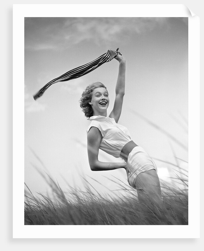 1950s 1960s Young Woman Bending Back Holding Scarf In The Wind Standing On Grassy Beach Dune by Anonymous