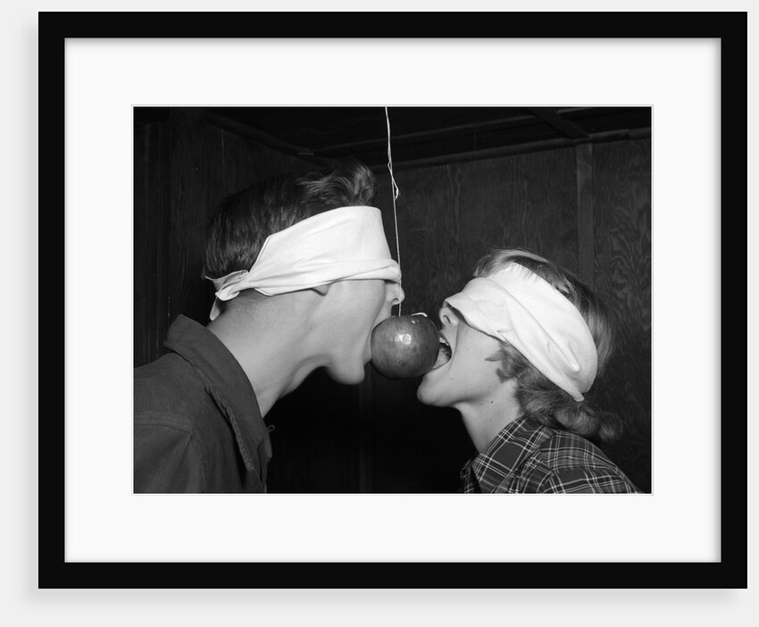 1950s Blindfolded Couple Trying To Eat An Apple Hanging In Air From A String Inside by Anonymous