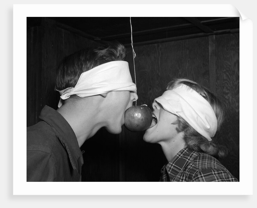 1950s Blindfolded Couple Trying To Eat An Apple Hanging In Air From A String Inside by Anonymous