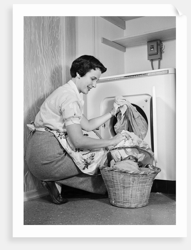 1950s Woman Kneeling Removing Clothes Laundry From Automatic Dryer by Anonymous