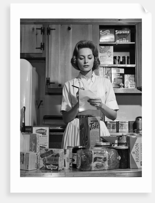 1960s Woman Housewife In Kitchen Checking Grocery Food Shopping List by Anonymous